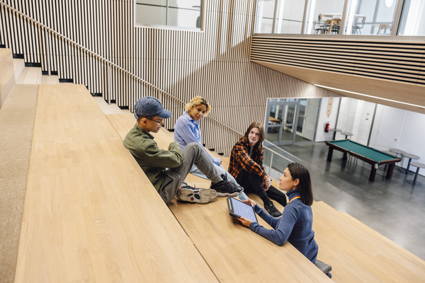 Aikuinen keskustelee kolmen nuoren kanssa koulun tiloissa.